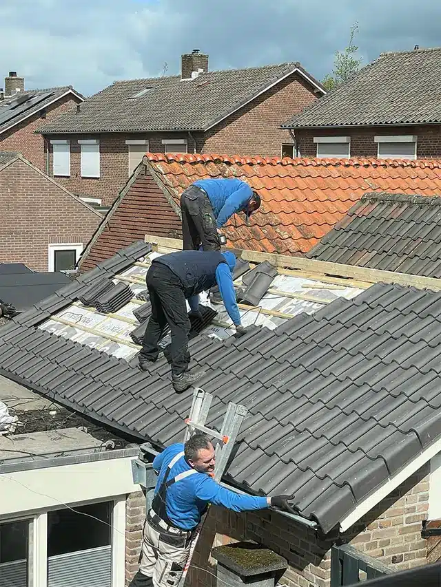 Dakdekkers van Grigorij Dakservice aan het werk op een pannendak